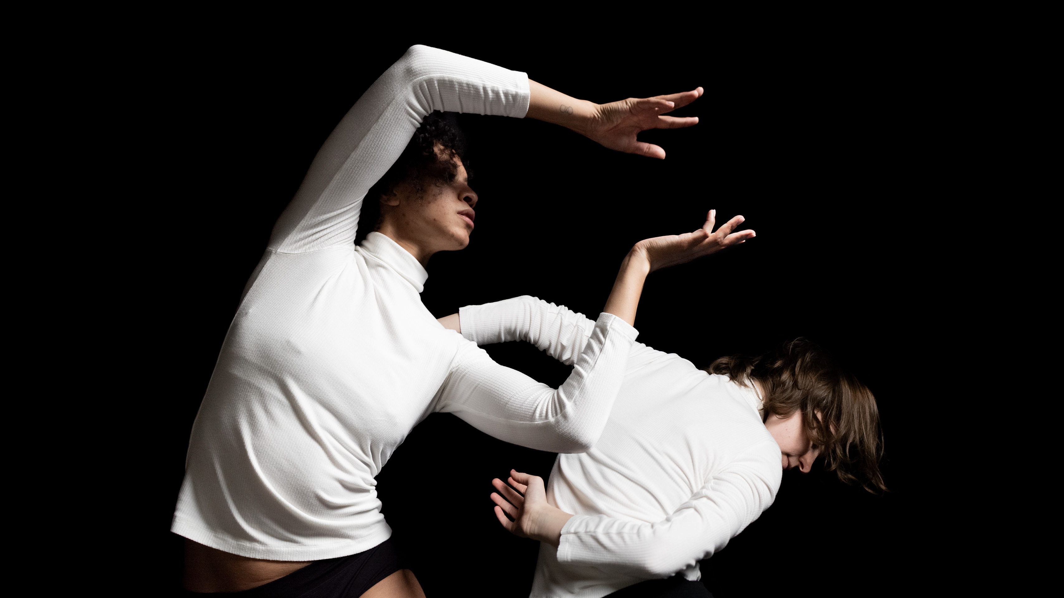 push/FOLD dancers Briley Jozwiak and Ashley Morton perform 'Wolf' at the Alberta Rose Theatre in Portland, Oregon. Photo depicts both dancers in white knit shirts in angular and gestural postures | Photography: Samuel Hobbs & Holly Shaw