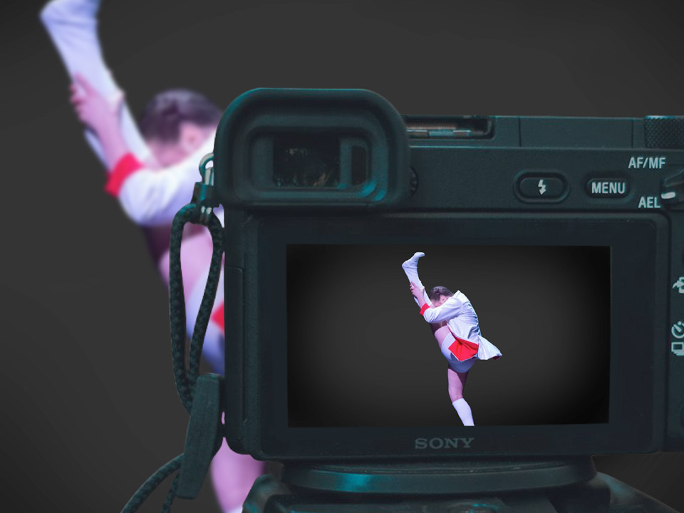 The Portland Ballet event image of a dancer holding a high kick in front of a film camera.