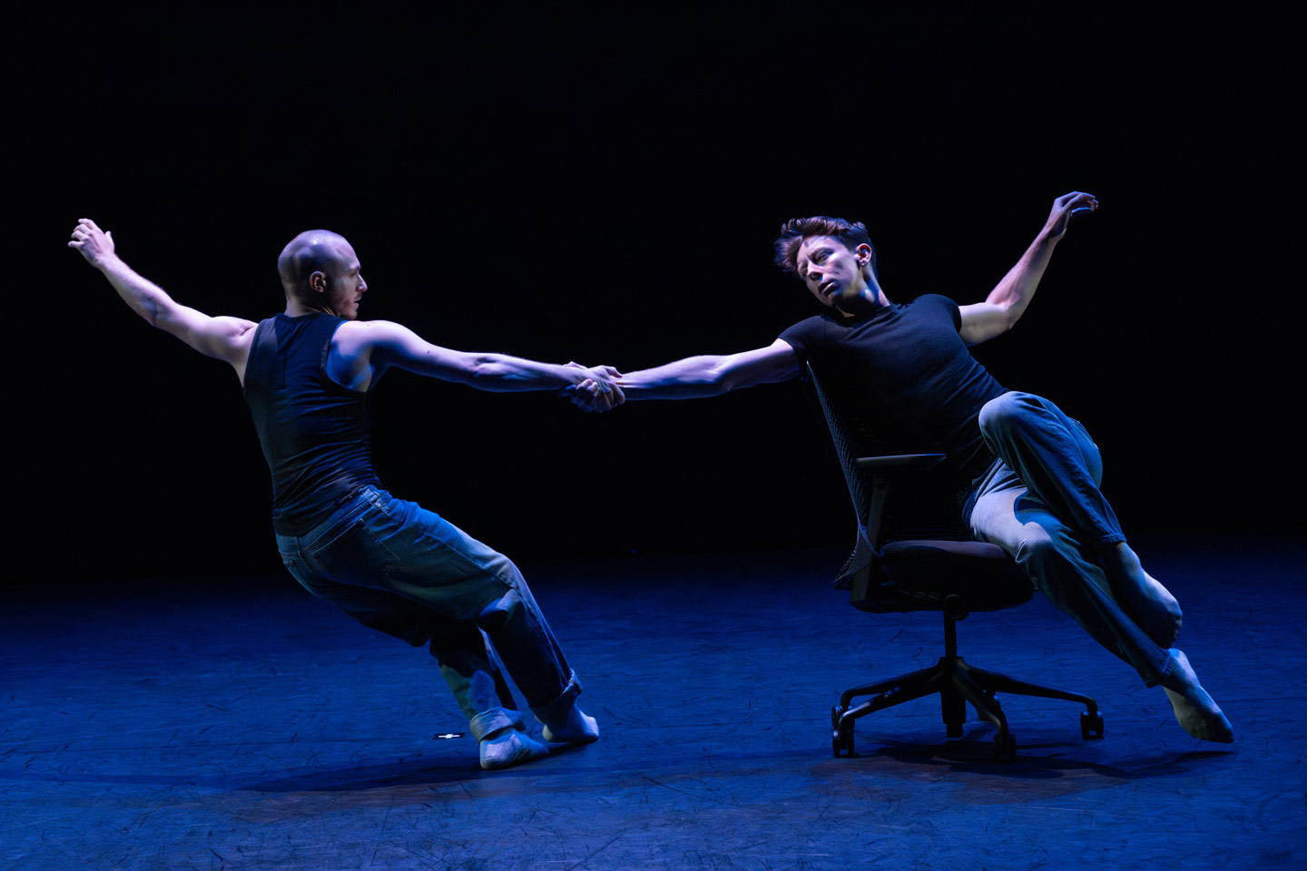 Union PDX - Festival:26 company VOLTA perform Mamie Green's work 'THE KID'. Photo depicts dancers Jordan Beasley and Ryley Polak with linked arms as one rides an office chair. | Photography: Jingzi Zhao